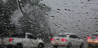 Foto do parabrisa de um carro com chuva, no lado de fora outros veículos circulando na rodovia sob chuva intensa, simbolizando o alerta laranja em Santa Catarina