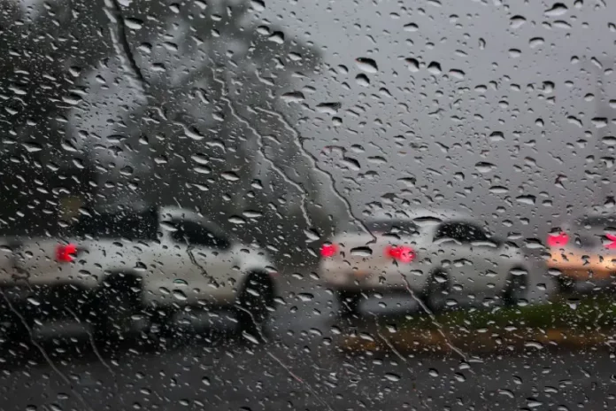 Foto do parabrisa de um carro com chuva, no lado de fora outros veículos circulando na rodovia sob chuva intensa, simbolizando o alerta laranja em Santa Catarina