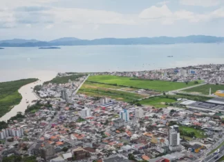 População de Biguaçu chega a 85.472 habitantes, aponta IBGE Vista aérea de Biguaçu mostra a área urbana do município, com prédios, casas, vias e a Baía Norte ao fundo, ilustrando a cidade que chegou a 85.472 habitantes em 2026.