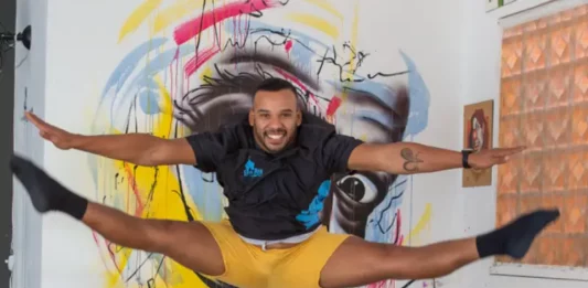 Artista salta em frente a mural colorido, em imagem que ilustra os novos editais da Política Nacional Aldir Blanc em São José.
