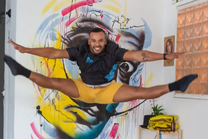 Artista salta em frente a mural colorido, em imagem que ilustra os novos editais da Política Nacional Aldir Blanc em São José.