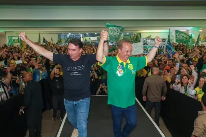Flávio Bolsonaro e Jorginho Mello Flávio Bolsonaro e Jorginho Mello aparecem de mãos levantadas diante de apoiadores durante ato de campanha em Santa Catarina.