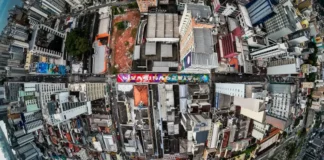 Vista aérea do Centro de Florianópolis, eleita a cidade mais criativa do Brasil, destaca prédios, ruas e intervenções de arte urbana, ilustrando a criatividade e a diversidade cultural da cidade.