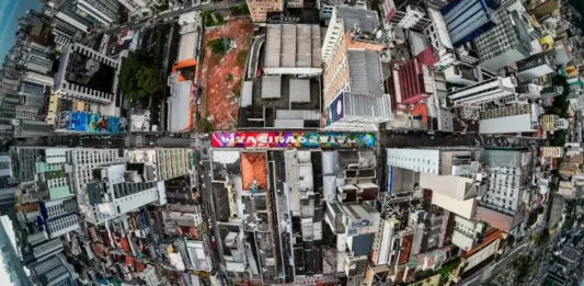 Vista aérea do Centro de Florianópolis, eleita a cidade mais criativa do Brasil, destaca prédios, ruas e intervenções de arte urbana, ilustrando a criatividade e a diversidade cultural da cidade.