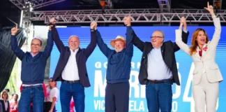 Lula e Gelson Merisio aparecem de mãos dadas com outras lideranças durante agenda de campanha em Florianópolis.