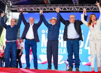 Lula e Gelson Merisio aparecem de mãos dadas com outras lideranças durante agenda de campanha em Florianópolis.