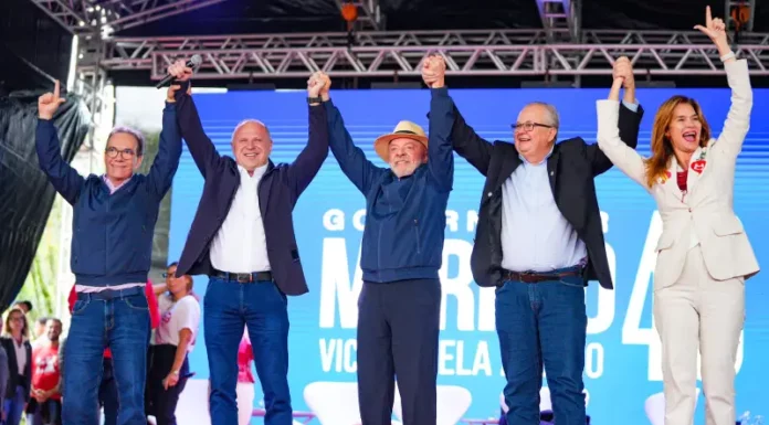 Lula e Gelson Merisio aparecem de mãos dadas com outras lideranças durante agenda de campanha em Florianópolis.
