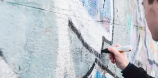 Artista pinta mural grafitado no Morro da Mariquinha, em Florianópolis, durante atividade de arte urbana.