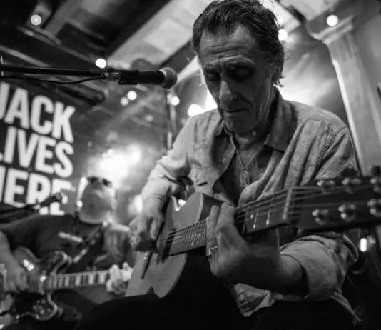 Músico toca guitarra durante apresentação de blues, imagem que ilustra o Praia do Rosa Blues Festival.