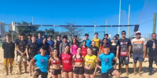 Jovens atletas e treinadores do projeto de vôlei de praia de São José posam em quadra de areia, representando a formação esportiva e o desenvolvimento de novos talentos no município.