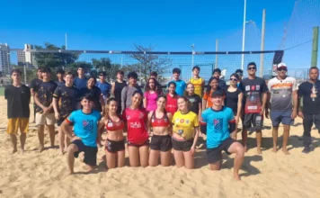Jovens atletas e treinadores do projeto de vôlei de praia de São José posam em quadra de areia, representando a formação esportiva e o desenvolvimento de novos talentos no município.
