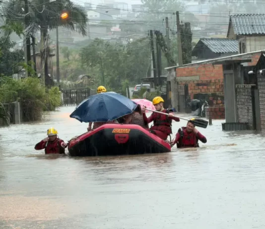 Bombeiros usam bote para resgatar moradores durante alagamentos em Criciúma.
