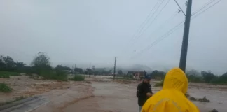 Alagamento toma via em Timbé do Sul durante as chuvas intensas, enquanto equipes acompanham a situação no município