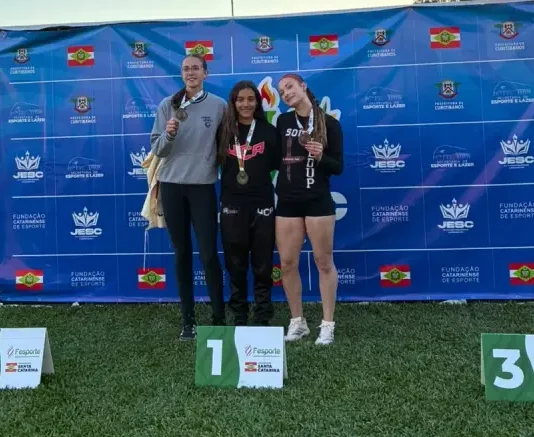 Maria Clara é campeã dos 100 metros com barreiras no Jesc e garante vaga nos Jogos da Juventude Maria Clara, ao centro, comemora a conquista do título dos 100 metros com barreiras no Jesc, em Curitibanos, ao lado de outras atletas.
