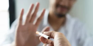 Texto alternativo: Pessoa segura um cigarro enquanto outra faz gesto de recusa, imagem que representa o tratamento para parar de fumar e o combate ao tabagismo.