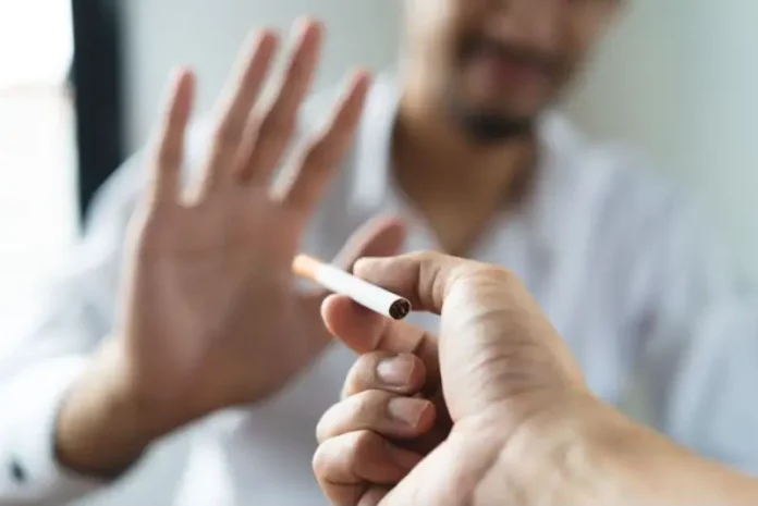 Texto alternativo: Pessoa segura um cigarro enquanto outra faz gesto de recusa, imagem que representa o tratamento para parar de fumar e o combate ao tabagismo.