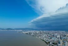 Semana terá mudança no tempo e aumento do risco de temporais em Santa Catarina Nuvens escuras de tempestade avançam sobre área urbana de Santa Catarina, imagem que ilustra o aumento do risco de temporais no estado.