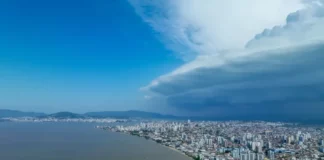 Nuvens escuras de tempestade avançam sobre área urbana de Santa Catarina, imagem que ilustra o aumento do risco de temporais no estado.