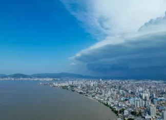 Nuvens escuras de tempestade avançam sobre área urbana de Santa Catarina, imagem que ilustra o aumento do risco de temporais no estado.
