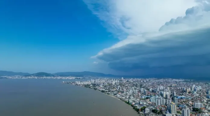 Semana terá mudança no tempo e aumento do risco de temporais em Santa Catarina Nuvens escuras de tempestade avançam sobre área urbana de Santa Catarina, imagem que ilustra o aumento do risco de temporais no estado.