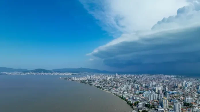 risco de temporais Nuvens escuras de tempestade avançam sobre área urbana de Santa Catarina, imagem que ilustra o aumento do risco de temporais no estado.
