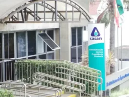 Casan prorroga inscrições de concurso com remuneração que pode passar de R$ 14 mil Fachada da sede administrativa da Casan, em Florianópolis, com entrada de vidro, rampa de acesso e placa de identificação da companhia