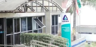 Fachada da sede administrativa da Casan, em Florianópolis, com entrada de vidro, rampa de acesso e placa de identificação da companhia
