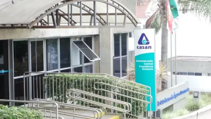 casan Fachada da sede administrativa da Casan, em Florianópolis, com entrada de vidro, rampa de acesso e placa de identificação da companhia