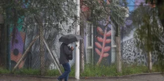 Pessoa caminha com guarda-chuva durante chuva intensa em Santa Catarina, onde a passagem de uma frente fria aumenta o risco de alagamentos e temporais.