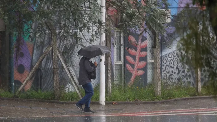 chuva-intensa Pessoa caminha com guarda-chuva durante chuva intensa em Santa Catarina, onde a passagem de uma frente fria aumenta o risco de alagamentos e temporais.
