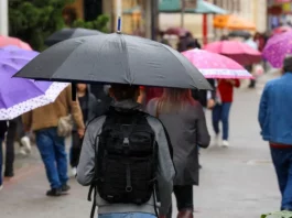 Pessoas caminham com guarda-chuvas durante chuva, imagem que ilustra a previsão de tempo instável em Santa Catarina.