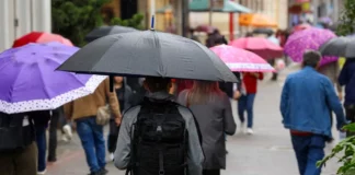 Pessoas caminham com guarda-chuvas durante chuva, imagem que ilustra a previsão de tempo instável em Santa Catarina.