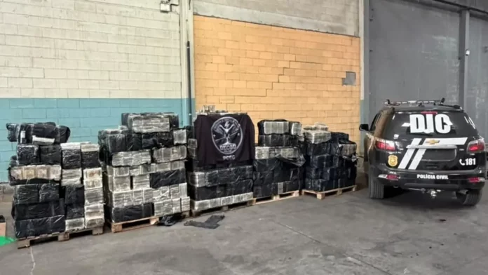 cocaina-policia-civil-1200x675 Pacotes de cocaína apreendidos pela Polícia Civil em Balneário Piçarras, durante a maior apreensão da droga da história de Santa Catarina, ao lado de uma viatura policial.