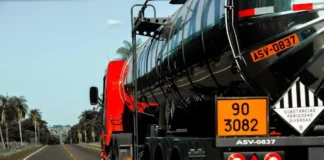 Caminhão-tanque com placas de identificação de produtos perigosos trafega por rodovia, ilustrando os riscos abordados no curso gratuito da Defesa Civil de SC.