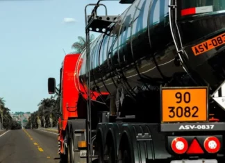 Caminhão-tanque com placas de identificação de produtos perigosos trafega por rodovia, ilustrando os riscos abordados no curso gratuito da Defesa Civil de SC.