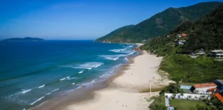 Vista aérea da Praia dos Açores, em Florianópolis, com faixa de areia, mar azul e morros cobertos por vegetação, uma das praias que conquistaram a certificação Bandeira Azul para a temporada 2026/2027.