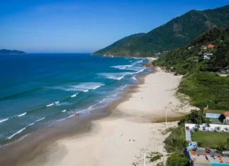 Vista aérea da Praia dos Açores, em Florianópolis, com faixa de areia, mar azul e morros cobertos por vegetação, uma das praias que conquistaram a certificação Bandeira Azul para a temporada 2026/2027.