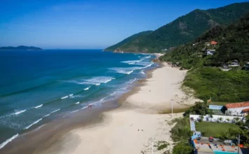 Mais três praias de Florianópolis conquistam certificação Bandeira Azul Vista aérea da Praia dos Açores, em Florianópolis, com faixa de areia, mar azul e morros cobertos por vegetação, uma das praias que conquistaram a certificação Bandeira Azul para a temporada 2026/2027.