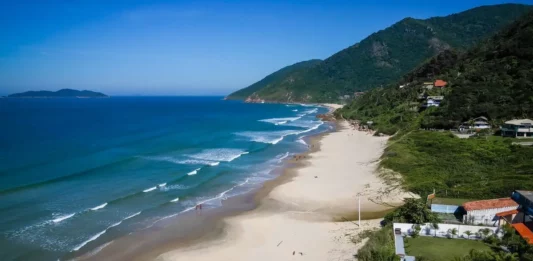 Mais três praias de Florianópolis conquistam certificação Bandeira Azul Vista aérea da Praia dos Açores, em Florianópolis, com faixa de areia, mar azul e morros cobertos por vegetação, uma das praias que conquistaram a certificação Bandeira Azul para a temporada 2026/2027.