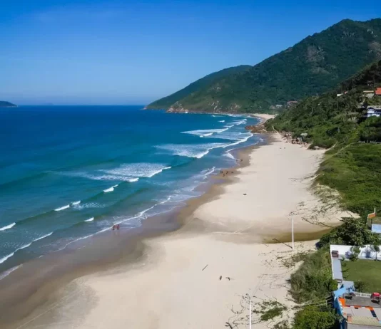 Mais três praias de Florianópolis conquistam certificação Bandeira Azul Vista aérea da Praia dos Açores, em Florianópolis, com faixa de areia, mar azul e morros cobertos por vegetação, uma das praias que conquistaram a certificação Bandeira Azul para a temporada 2026/2027.