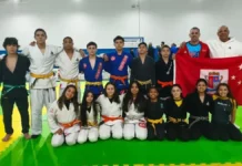 São José conquista título na ginástica e medalhas no jiu-jítsu e taekwondo na Olesc 2026 Equipe de jiu-jítsu de São José posa com treinadores e bandeira do município durante a Olesc 2026.