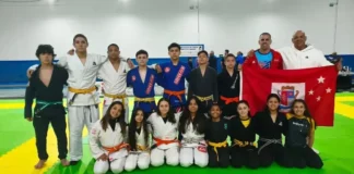 Equipe de jiu-jítsu de São José posa com treinadores e bandeira do município durante a Olesc 2026.