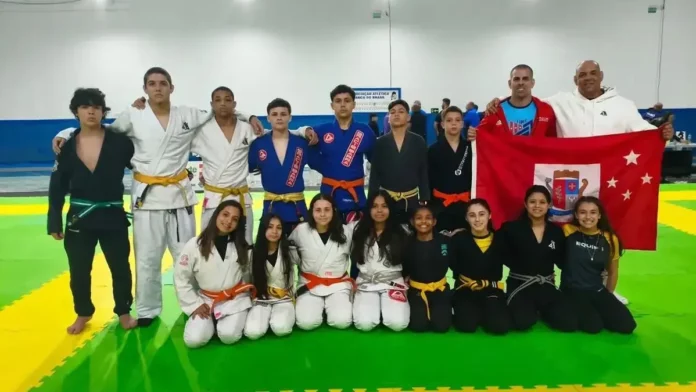 jiu-jitsu-sao-jose-olesc-2026 Equipe de jiu-jítsu de São José posa com treinadores e bandeira do município durante a Olesc 2026.