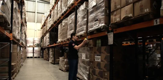 Santa Catarina adota metodologia para evitar desperdício de dinheiro público em licitações Trabalhador confere produtos armazenados em depósito, ilustrando as compras públicas e o controle de gastos em licitações de Santa Catarina.