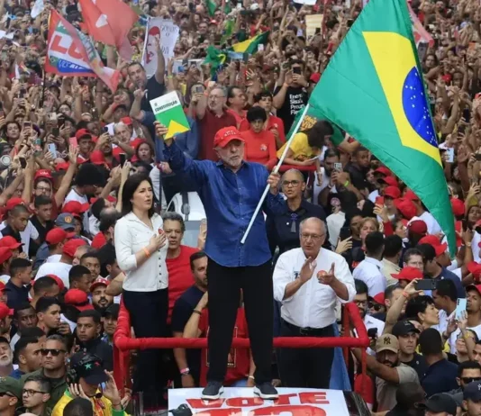 Lula é reeleito presidente do Brasil para o quarto mandato Lula segura a bandeira do Brasil diante de uma multidão de apoiadores em ato político. Presidente foi reeleito para o quarto mandato em 2026.