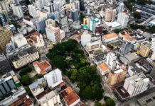 Florianópolis terá oficinas para ouvir moradores sobre problemas no trânsito e transporte Vista aérea do Centro de Florianópolis, com prédios, ruas e áreas arborizadas, ilustrando os desafios do trânsito e transporte na Capital e a discussão sobre mobilidade urbana.