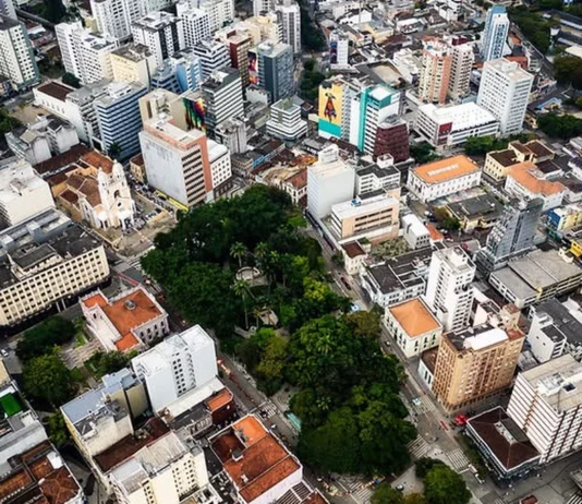 Vista aérea do Centro de Florianópolis, com prédios, ruas e áreas arborizadas, ilustrando os desafios do trânsito e transporte na Capital e a discussão sobre mobilidade urbana.