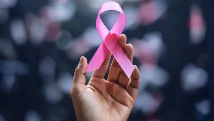 Mão segura laço rosa, símbolo do Outubro Rosa, campanha de conscientização sobre a prevenção e o diagnóstico precoce do câncer de mama.