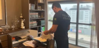 Agente da Polícia Federal examina documentos durante operação que investiga irregularidades na previdência dos servidores de Palhoça, em Santa Catarina.