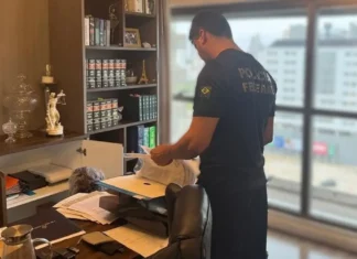 Agente da Polícia Federal examina documentos durante operação que investiga irregularidades na previdência dos servidores de Palhoça, em Santa Catarina.